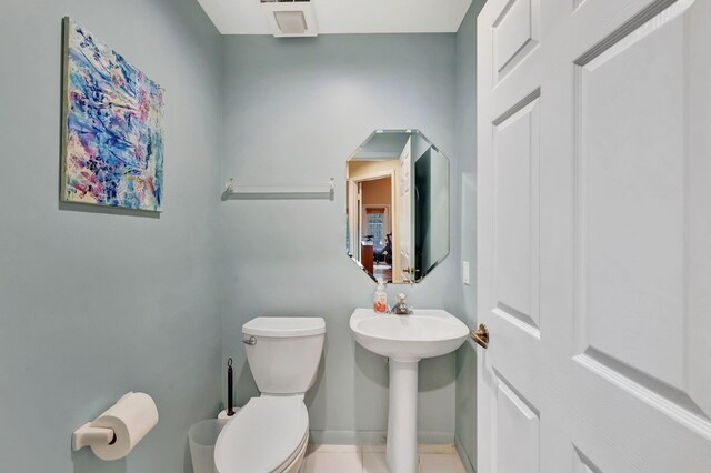 bathroom featuring toilet, a sink, tile patterned floors, and baseboards