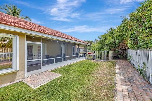 view of yard featuring a sunroom, french doors, and a fenced backyard