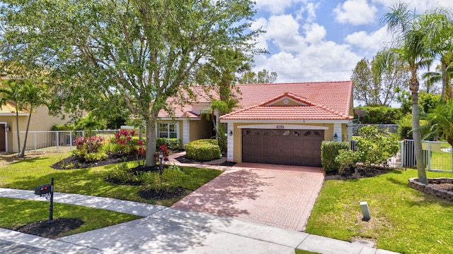 mediterranean / spanish-style home featuring fence, stucco siding, a tiled roof, and an attached garage