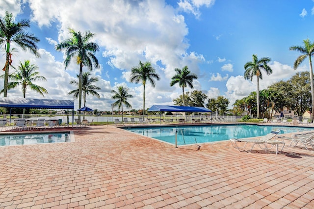 community pool with fence and a patio area