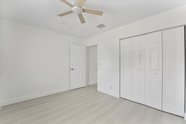unfurnished bedroom featuring visible vents, a closet, baseboards, ceiling fan, and light wood-style flooring
