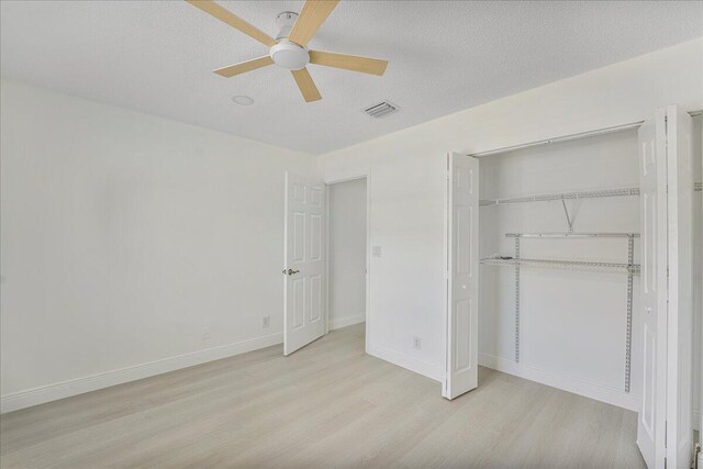 unfurnished bedroom with a ceiling fan, baseboards, wood finished floors, visible vents, and a closet