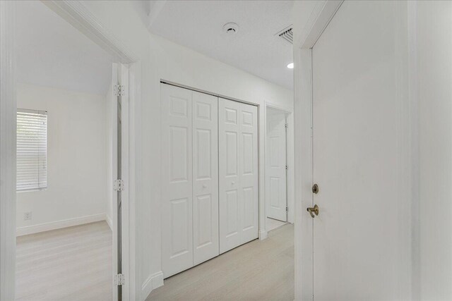 hall with light wood-style floors, baseboards, and visible vents