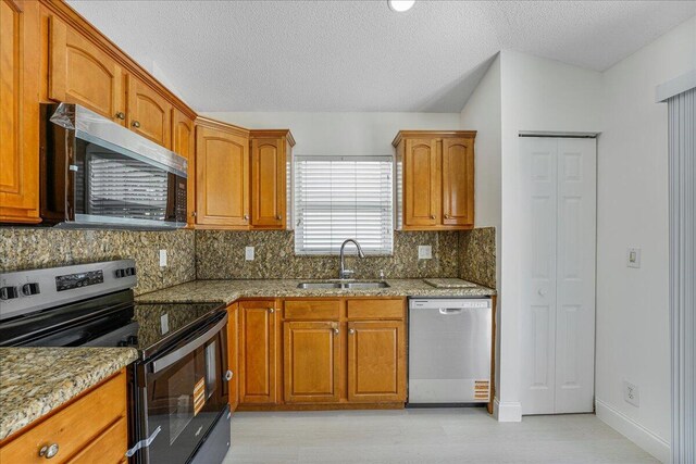 kitchen featuring a sink, appliances with stainless steel finishes, tasteful backsplash, and light stone counters