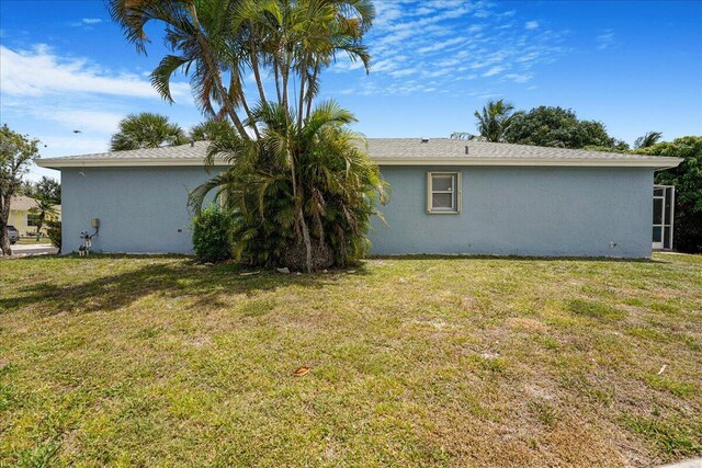 rear view of property featuring a yard and stucco siding