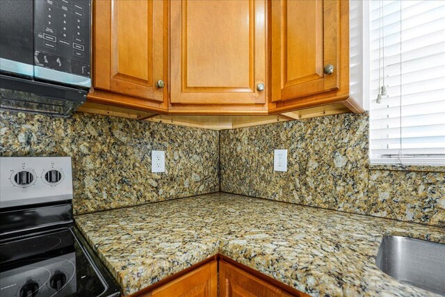 interior details with a sink, decorative backsplash, stainless steel appliances, and brown cabinets