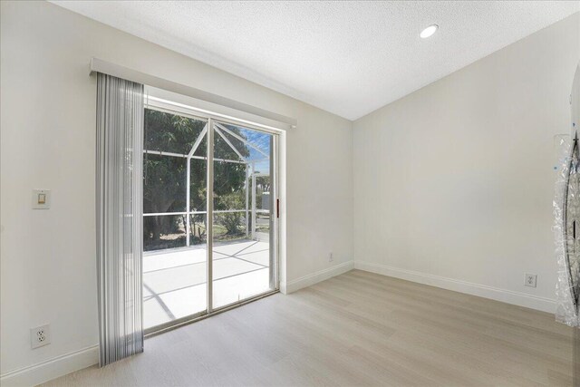 spare room with baseboards, a textured ceiling, and wood finished floors