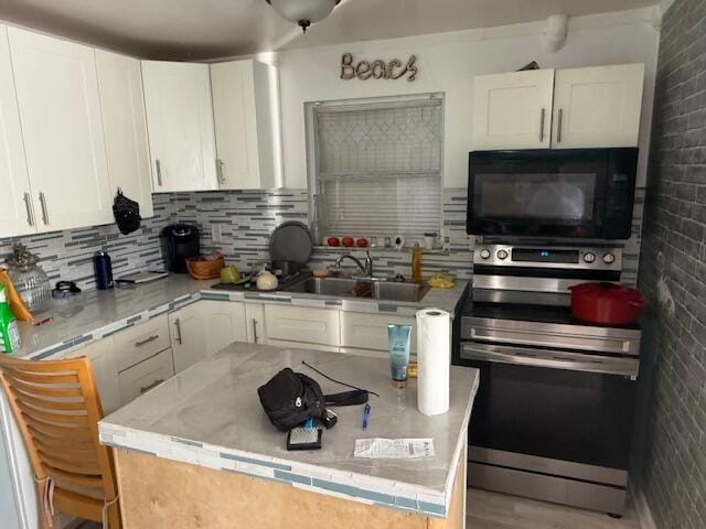 1126 S L St, Lake Worth Beach, FL 33460 - kitchen featuring white cabinetry, black microwave, a sink, and stainless steel range with electric stovetop