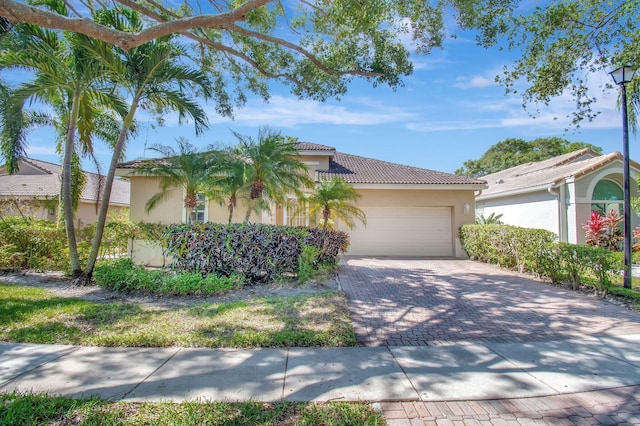 view of front of home with stucco siding, an attached garage, driveway, and a tiled roof