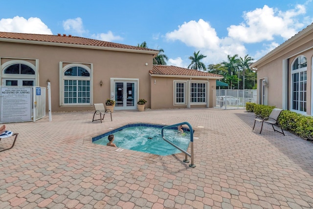 view of swimming pool featuring a hot tub, a patio area, french doors, and fence