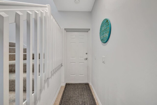 doorway featuring baseboards and stairway