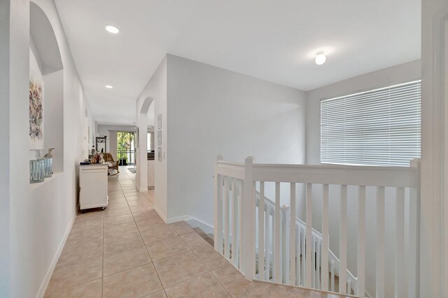 hall with baseboards, recessed lighting, light tile patterned floors, and an upstairs landing