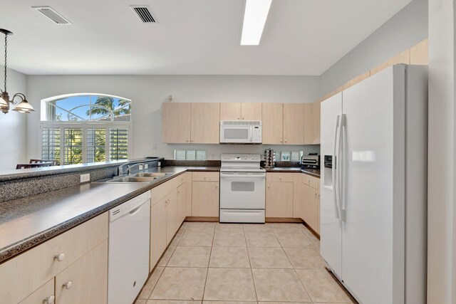 kitchen with visible vents, light brown cabinetry, dark countertops, a sink, and white appliances