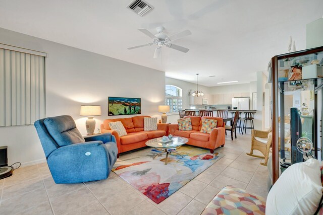 living area featuring light tile patterned floors, baseboards, ceiling fan with notable chandelier, and visible vents