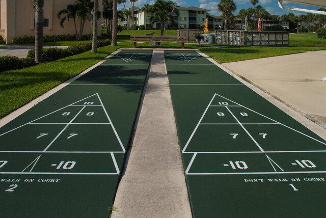 view of community with a yard, fence, and shuffleboard