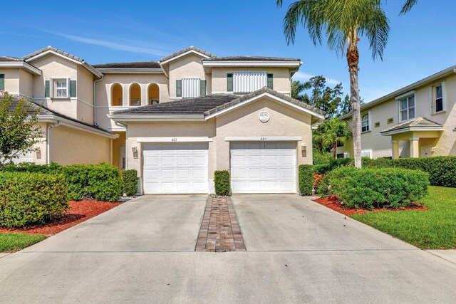 view of front facade with a garage, stucco siding, driveway, and a tile roof