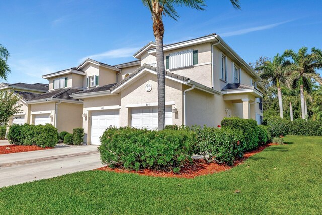 view of front of home with an attached garage, driveway, a front yard, and stucco siding