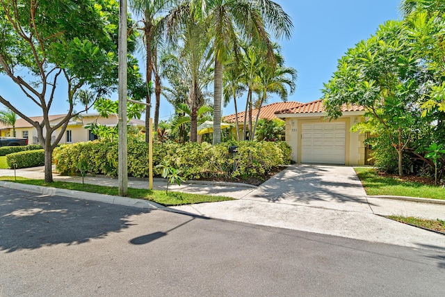 view of front facade with stucco siding, a tile roof, concrete driveway, and an attached garage