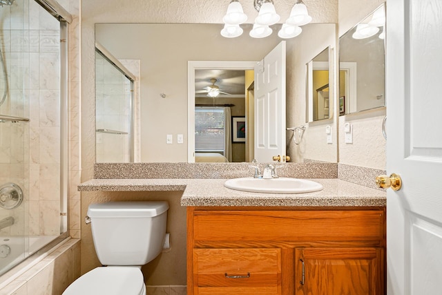 ensuite bathroom with tiled shower / bath combo, connected bathroom, ceiling fan, toilet, and vanity