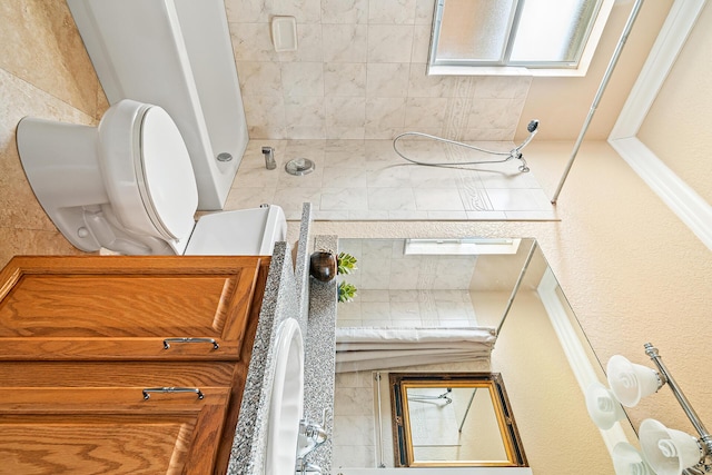 full bathroom featuring toilet and tiled shower