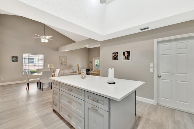 kitchen featuring ceiling fan, light wood-style floors, light countertops, open floor plan, and visible vents