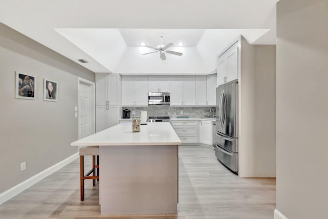 4059 Gator Trace Rd, Fort Pierce, FL 34982 - kitchen with stainless steel appliances, a ceiling fan, a kitchen island, tasteful backsplash, and light wood-type flooring