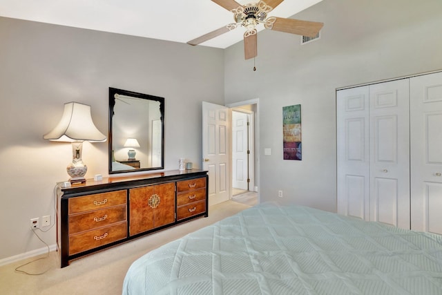bedroom featuring ceiling fan, a towering ceiling, baseboards, a closet, and light carpet