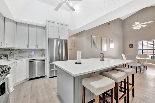 4059 Gator Trace Rd, Fort Pierce, FL 34982 - kitchen featuring stainless steel appliances, ceiling fan, a sink, light wood finished floors, and high vaulted ceiling