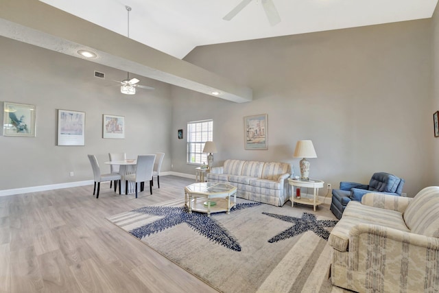 living area with visible vents, wood finished floors, baseboards, high vaulted ceiling, and a ceiling fan