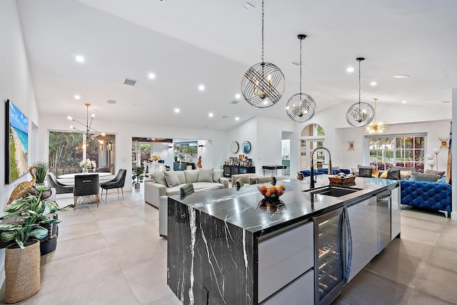 kitchen with modern cabinets, a sink, beverage cooler, lofted ceiling, and open floor plan