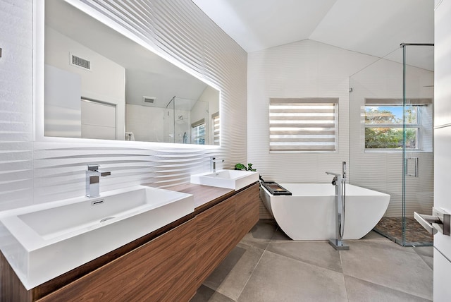 bathroom featuring visible vents, a freestanding tub, a shower stall, a sink, and vaulted ceiling