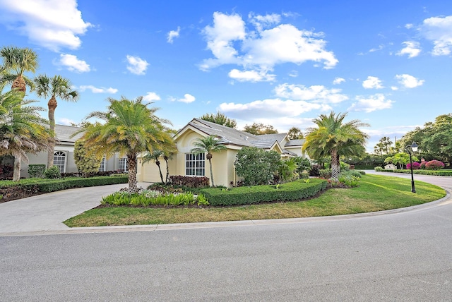 view of front facade featuring a garage, stucco siding, concrete driveway, and a front yard