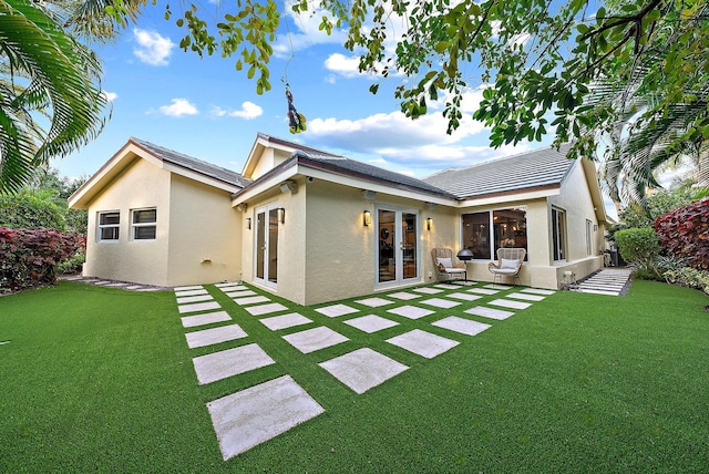 rear view of property with a patio, a yard, stucco siding, and french doors