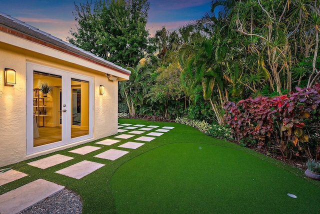 yard at dusk featuring french doors