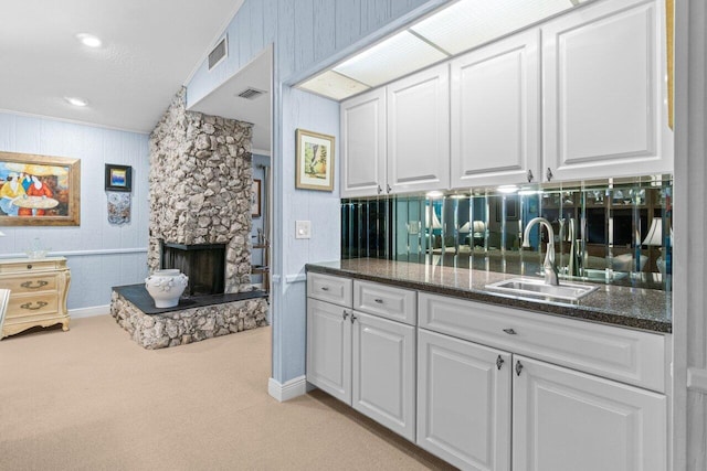 interior space featuring light colored carpet, a sink, white cabinetry, and visible vents
