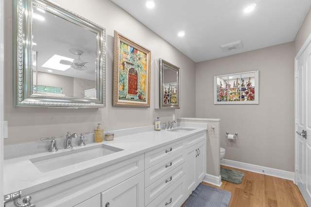 bathroom with baseboards, a sink, wood finished floors, and toilet