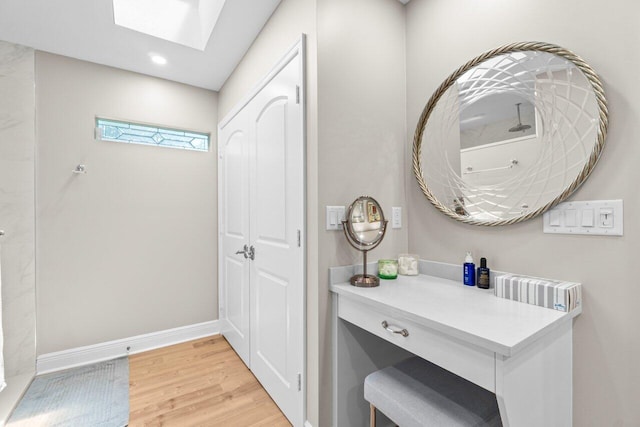 bathroom with a skylight, baseboards, recessed lighting, and wood finished floors