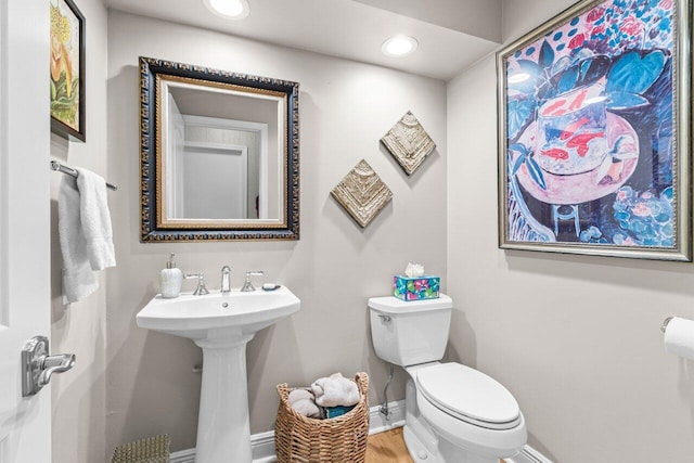 half bath with a sink, toilet, recessed lighting, baseboards, and wood finished floors