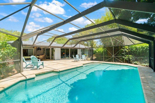 outdoor pool featuring glass enclosure and a patio