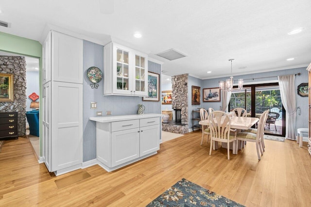 dining room featuring recessed lighting, light wood-type flooring, a stone fireplace, and a chandelier