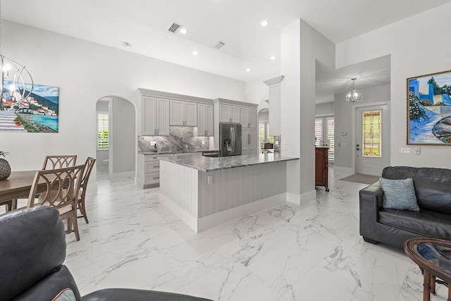 3352 SE Cascadia Way, Hobe Sound, FL 33455 - kitchen with visible vents, light stone countertops, open floor plan, stainless steel fridge with ice dispenser, and arched walkways