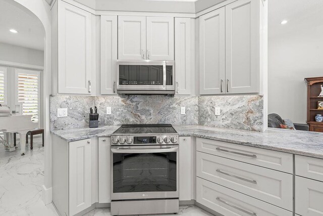 3352 SE Cascadia Way, Hobe Sound, FL 33455 - kitchen featuring arched walkways, stainless steel appliances, light stone counters, and marble finish floor