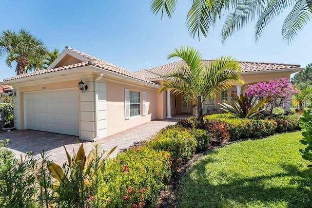 3352 SE Cascadia Way, Hobe Sound, FL 33455 - mediterranean / spanish-style house featuring an attached garage, stucco siding, driveway, and a tile roof