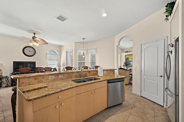 kitchen featuring a ceiling fan, visible vents, a sink, open floor plan, and stainless steel appliances