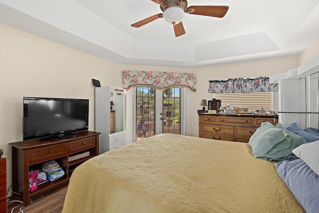 bedroom featuring access to outside, wood finished floors, a raised ceiling, and ceiling fan