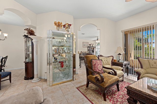 living room with a ceiling fan, tile patterned flooring, baseboards, and arched walkways