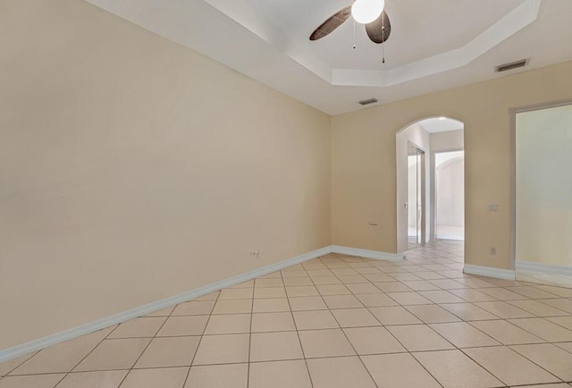 7562 Starfish Reef Ln, Lake Worth, FL 33467 - empty room featuring arched walkways, ceiling fan, a tray ceiling, light tile patterned floors, and baseboards
