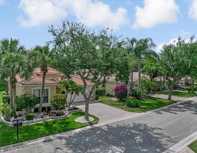 7562 Starfish Reef Ln, Lake Worth, FL 33467 - view of front of property with driveway, stucco siding, a tiled roof, an attached garage, and a front yard