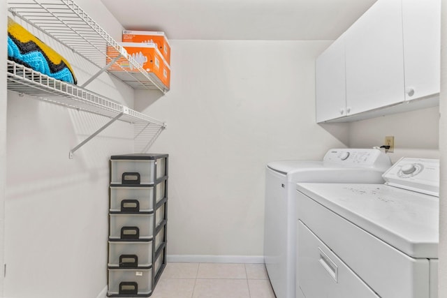 laundry area featuring light tile patterned floors, baseboards, cabinet space, and washer and clothes dryer