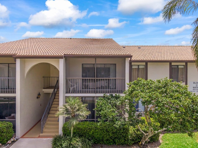 view of front of home featuring stucco siding, a tile roof, and stairway